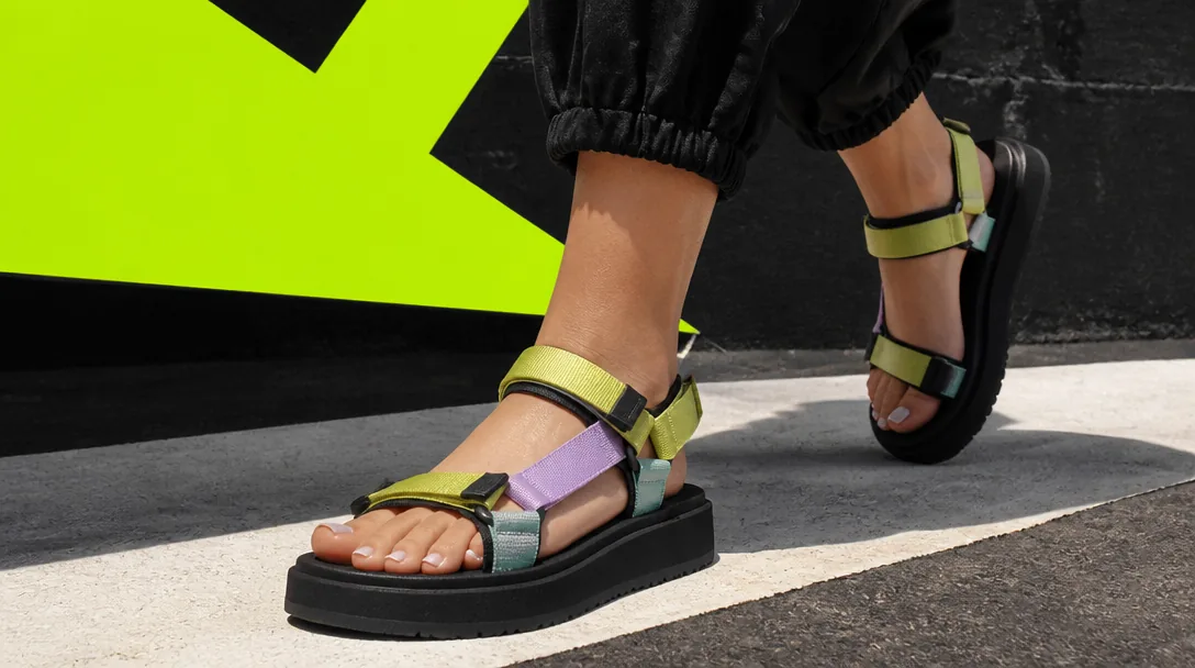 Kvinna i bekväma sommarsandaler på stadsgata, bold streetwear editorial med acid-lime accenter